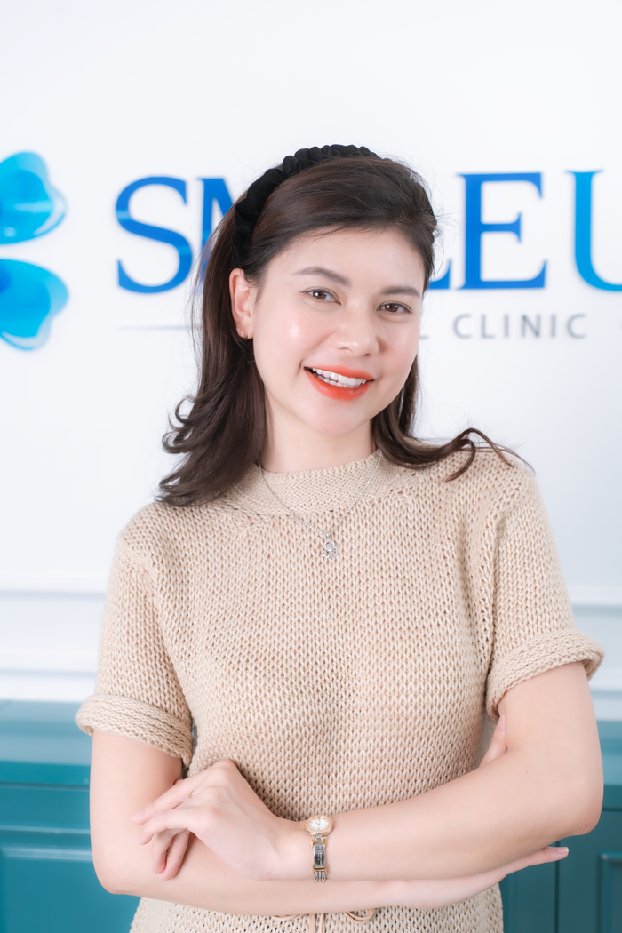 Friendly woman posing at a dental clinic reception area, exuding warmth and approachability.
