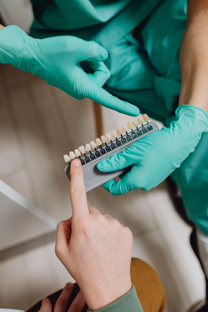 Close-up of hands holding a tooth shade guide in a dental setting.
