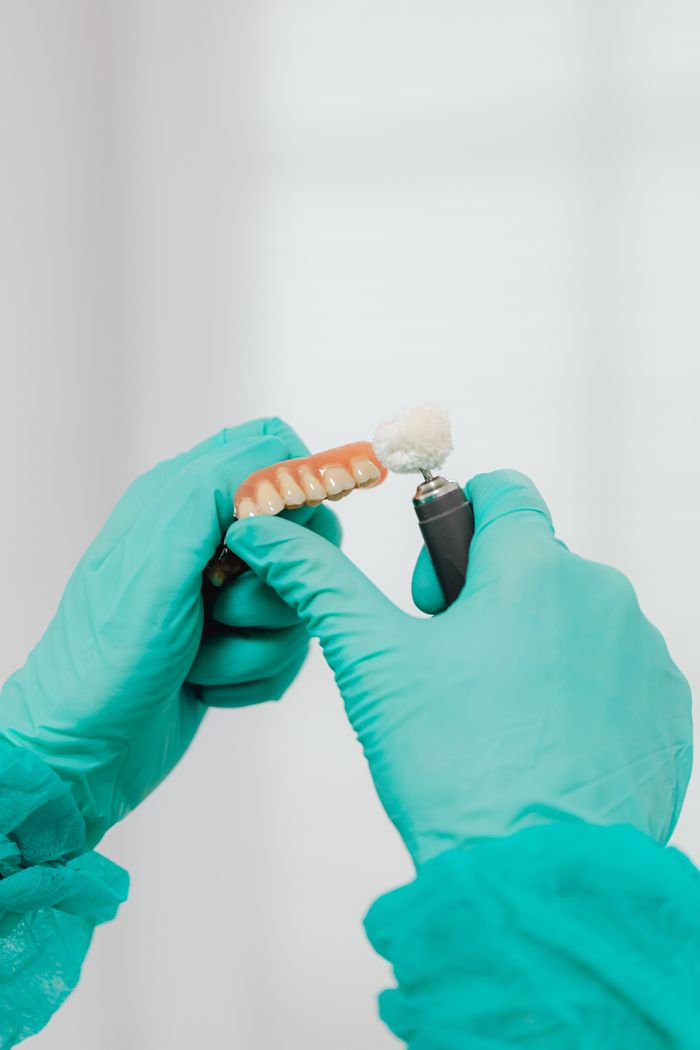 Close-up of a dentist polishing a denture, showcasing dental care and hygiene.