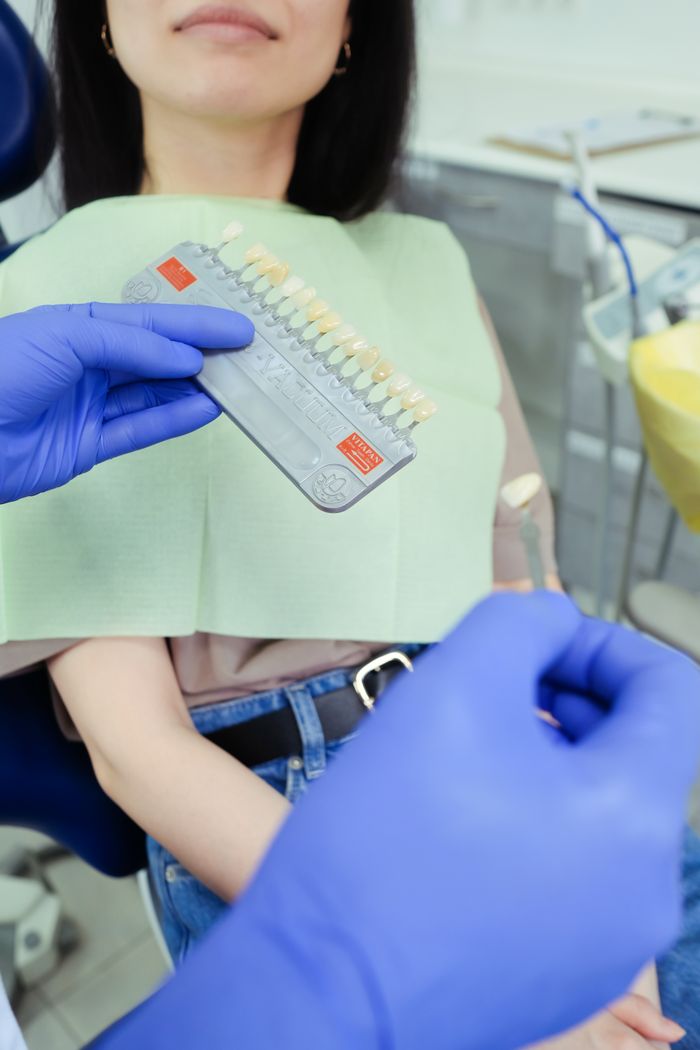 Dentist compares patient's teeth with a color chart in a modern clinic, emphasizing dental care.